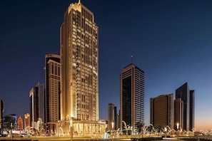 Un immeuble de grande hauteur doté d’une architecture moderne, caractérisé par une structure verticale imposante et des fenêtres illuminées.