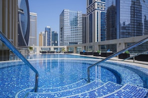Une piscine intérieure moderne, aux carreaux bleu clair, entourée d’immeubles de grande hauteur.