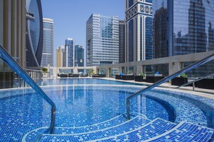 Una piscina al aire libre, sombrillas, sillones reclinables de piscina