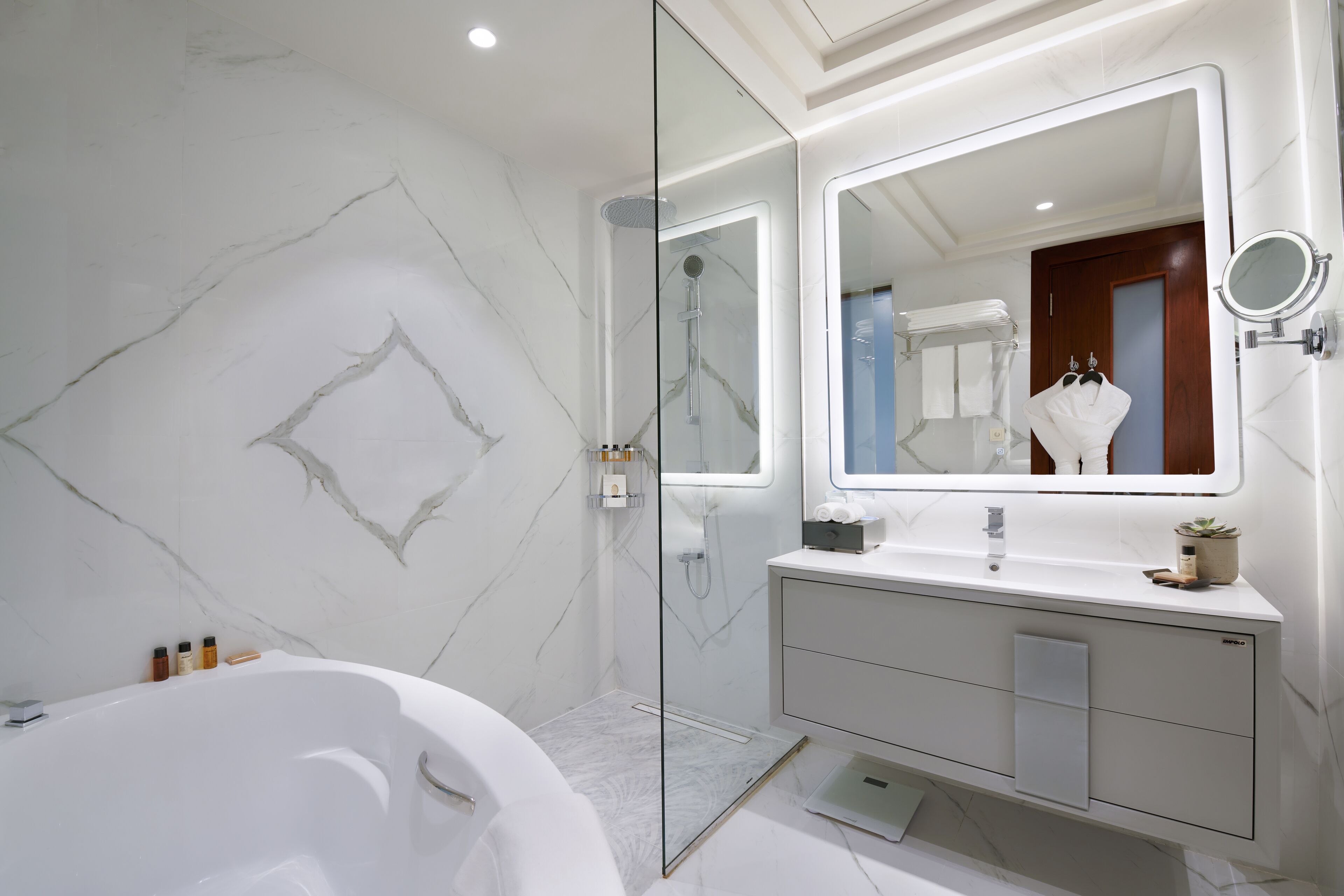A modern bathroom with a glass-enclosed shower, a freestanding bathtub, and a vanity with a mirror.