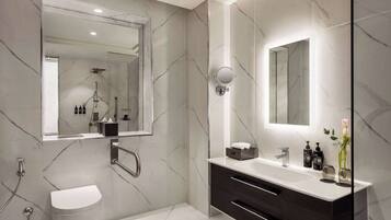 A modern bathroom with a large mirror, a toilet, a vanity with a sink, and a shower area.