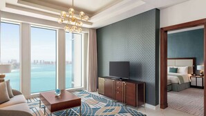 Une chambre d’hôtel moderne dotée d’une grande fenêtre donnant sur la ville, d’un téléviseur à écran plat posé sur un meuble en bois, d’un canapé et d’un tapis à motifs.