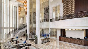 Un hall d’entrée spacieux, agrémenté d’un grand escalier, de coins salon et d’un comptoir d’accueil.