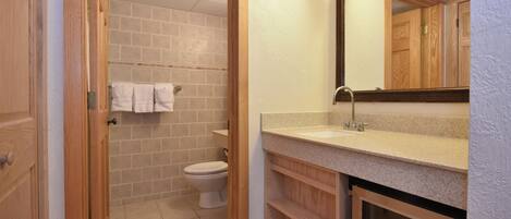 A bathroom with a toilet, a sink, and a mirror.