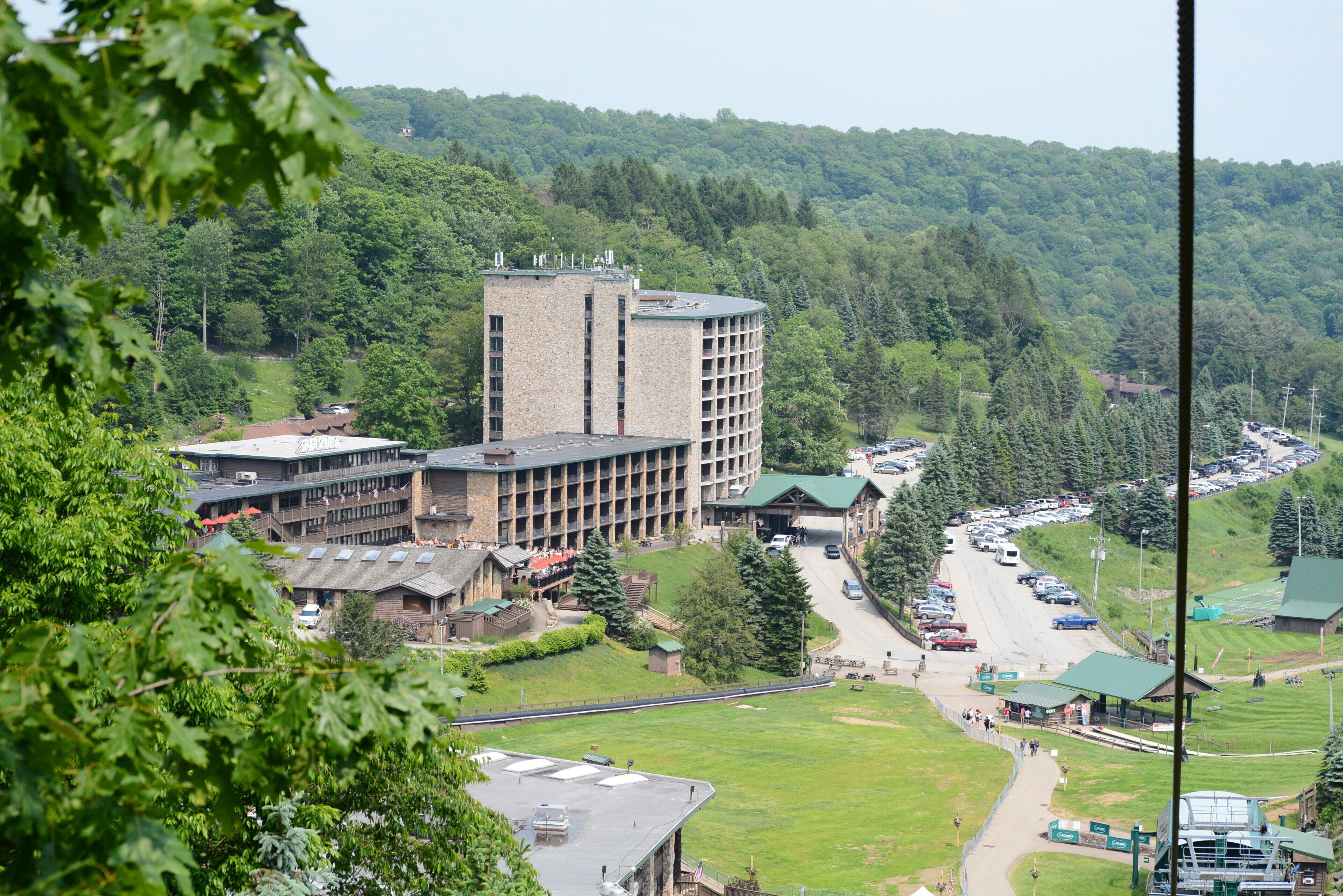 A multi-story building with a central courtyard, surrounded by lush greenery and a parking area.