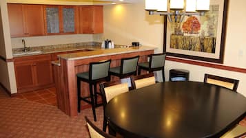 A kitchen with wooden cabinets, a granite countertop, and a dining area with a round table and chairs.