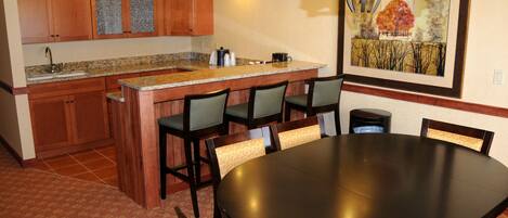 Una cocina con armarios de madera, encimera de granito y comedor con mesa y sillas redondas.