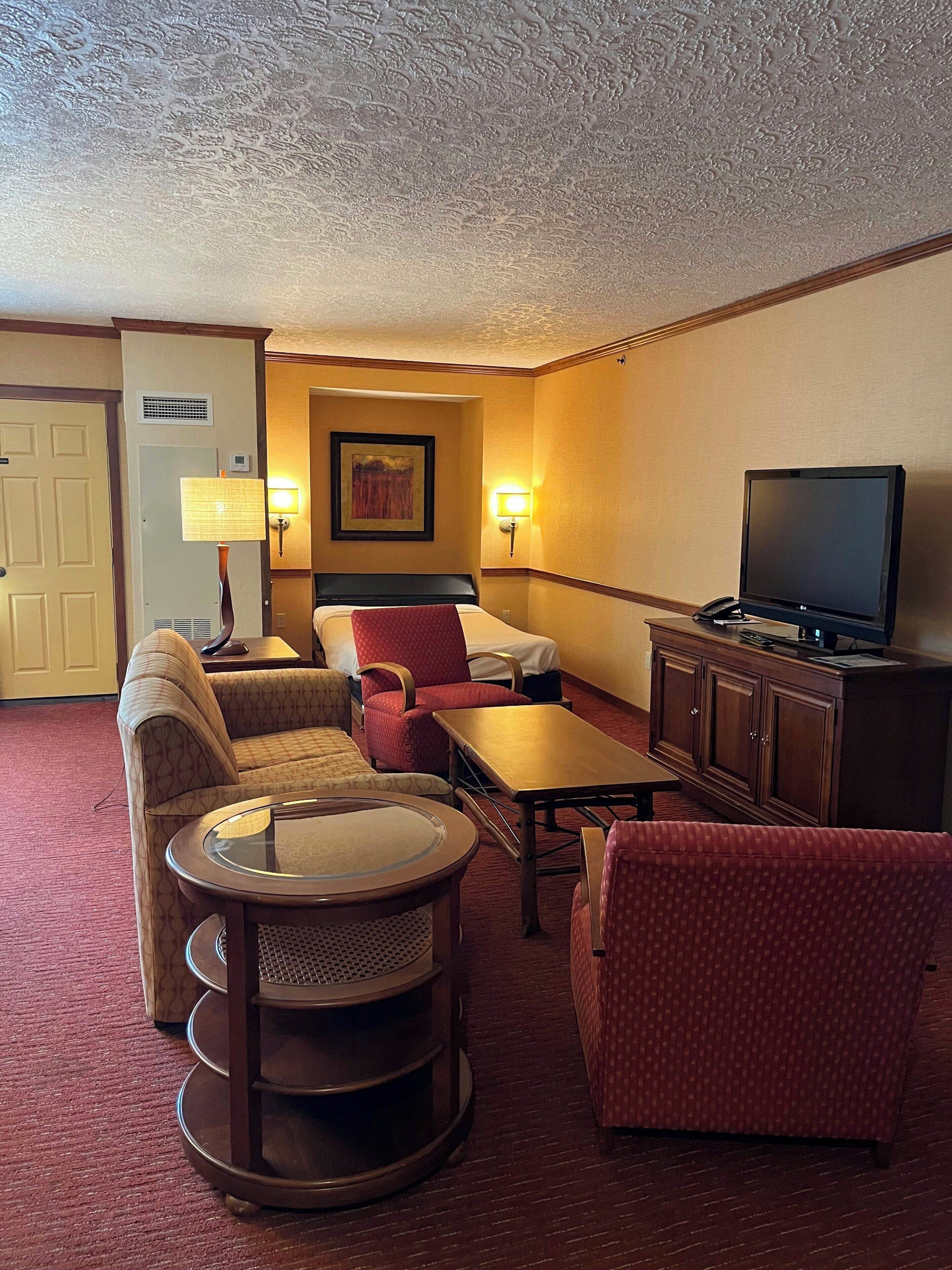 Una habitación de hotel con cama, televisión, escritorio, silla y una mesita.