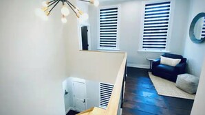 A modern interior with a staircase, a black leather sofa, and a ceiling light fixture. - Newly Renovated 3 Bed, 2 Bath Apartm! 24/7 Service (Covington)