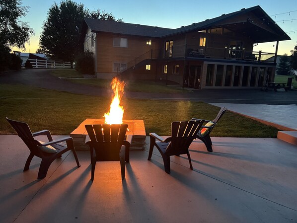 Relax by the fire pit in a serene outdoor seating area, surrounded by Adirondack chairs.