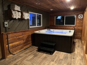 Relax in a spacious hot tub with a clear water level indicator, accompanied by a comfortable bench and step stool for easy access.