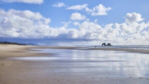 Ein Strand mit blauem Himmel und einer Felsformation in der Ferne.