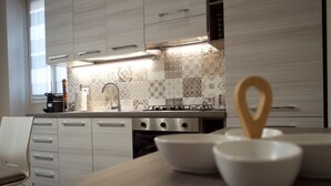 Een moderne keuken met lichte houten kastjes, een gasfornuis en een backsplash met patroontegels.