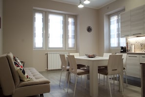 A modern kitchen with a dining table, chairs, and a sofa.