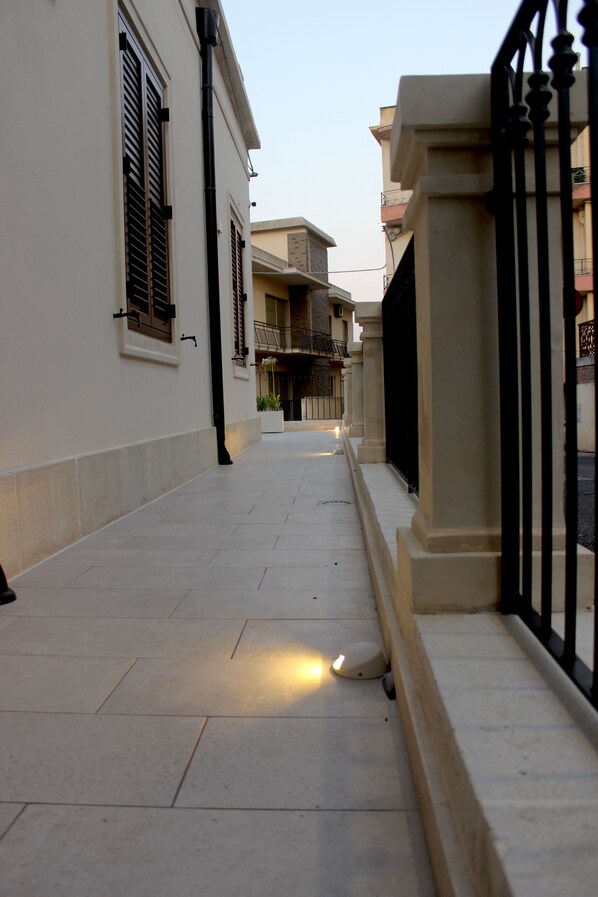 Un estrecho sendero empedrado flanqueado por edificios con balcones y una entrada porticada.