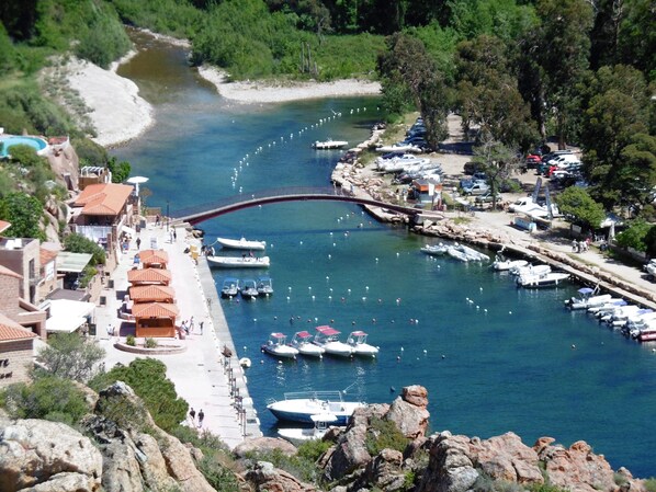 A coastal marina with boats docked, a bridge, and buildings along the waterfront.