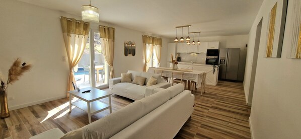 A modern living room with a sofa, dining table, and kitchen area.
