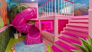 Un área de juegos interior, muy colorida, con un tobogán, escaleras y un mural.
