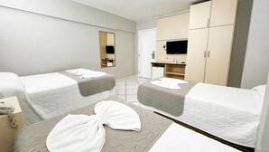 Habitación de hotel con dos camas, un televisor, un armario y un pequeño escritorio con teléfono.