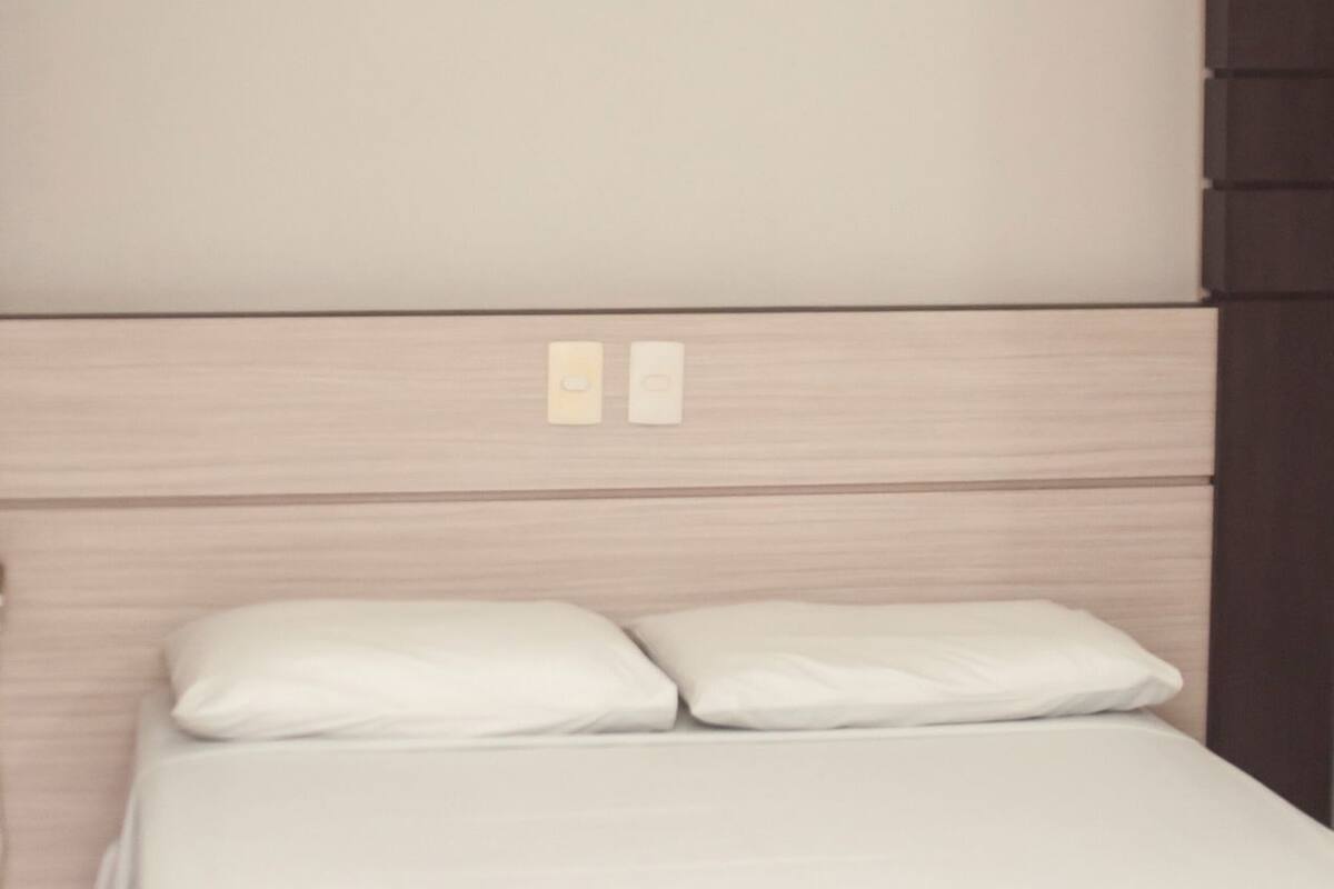 A bed with white bedding and a wooden headboard.