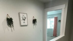 A staircase with a white handrail leading to a landing. There are two wall-mounted planters with greenery. A framed picture hangs on the wall.