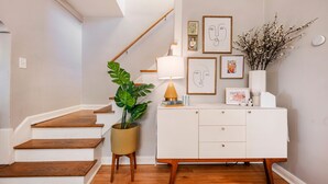 A staircase with wooden steps and a white wall with framed artwork and a vase of flowers. - BEST LOCATION DOWNTOWN, DESIGNER FURNISHINGS (Salt Lake City)