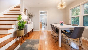 A modern kitchen with wooden stairs, a dining area with a table and chairs, and a hallway leading to another room. - BEST LOCATION DOWNTOWN, DESIGNER FURNISHINGS (Salt Lake City)