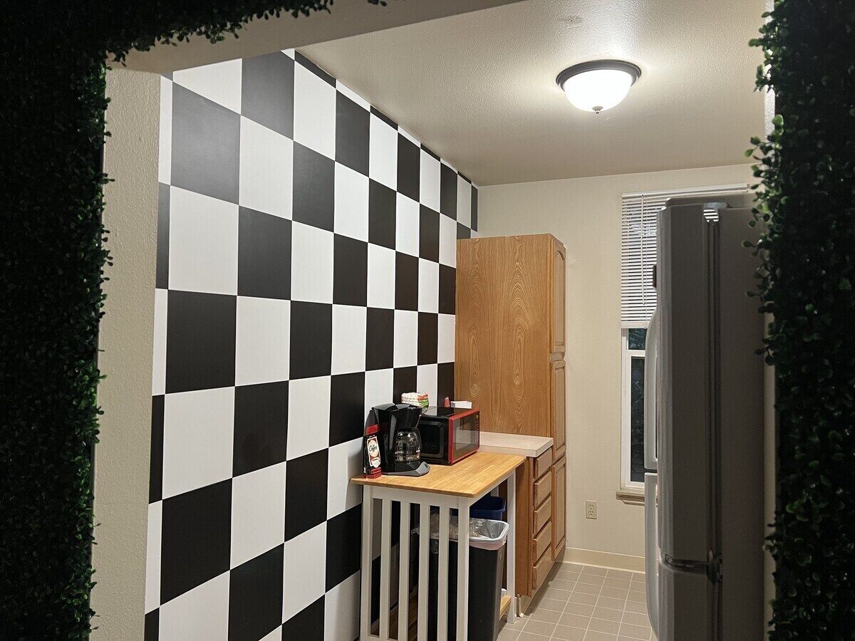 A compact kitchen with a checkered backsplash, a coffee maker, and a microwave on a small counter.