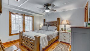 A bedroom with a wooden bed, a nightstand, a lamp, and a ceiling fan. - Cozy Mount Dora Cottage /Walk Downtown/ Pet Friendly / Fenced Yard (Mount Dora)