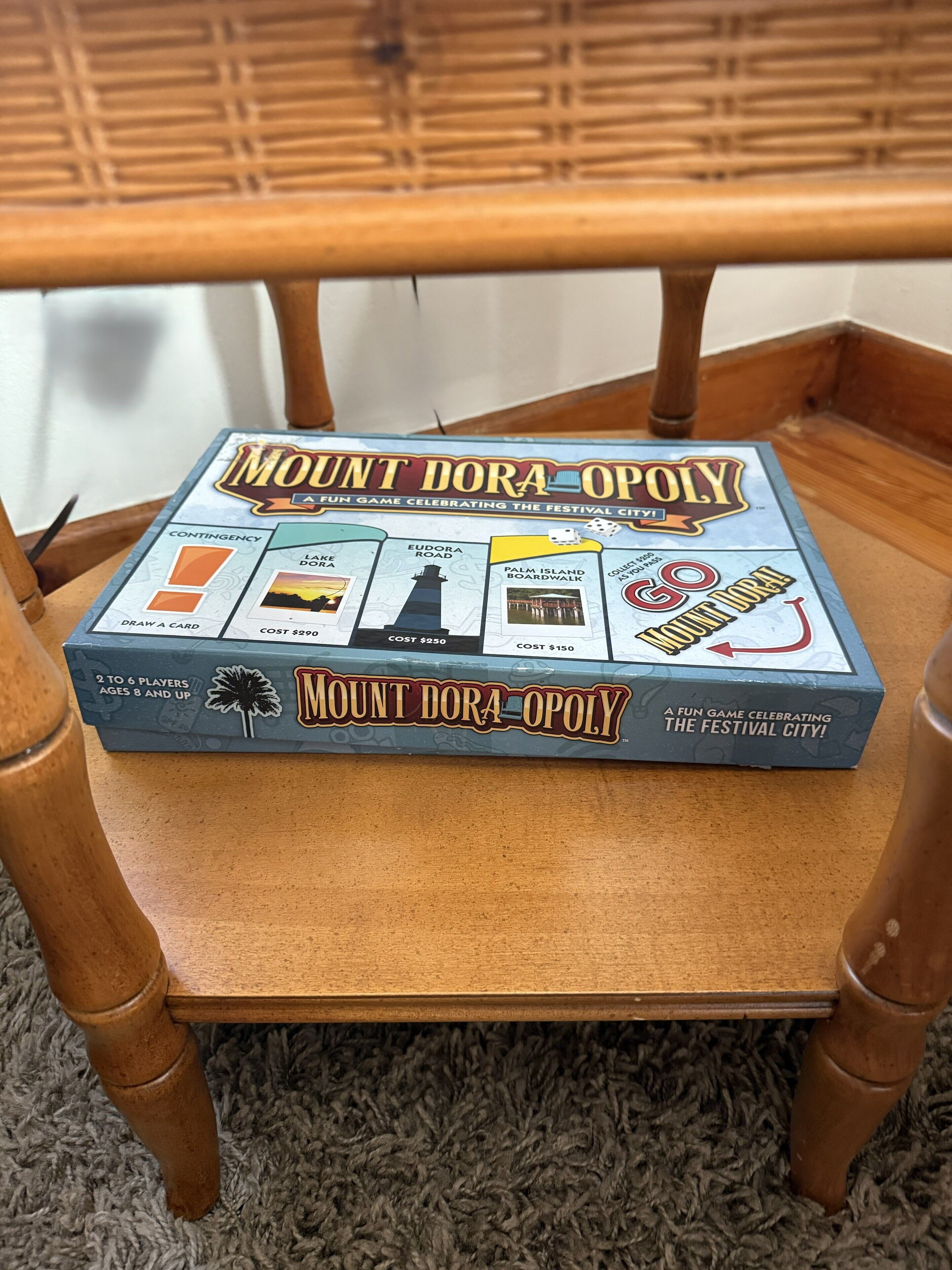 Un juego de mesa llamado "Mount Dora Opoly" sobre una silla de madera.