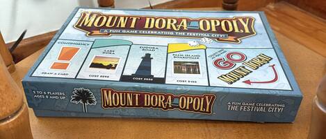 Un juego de mesa llamado "Mount Dora Opoly" sobre una silla de madera.