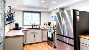 Una cocina moderna con refrigerador de acero inoxidable, encimeras de madera y un ventanal que proporciona luz natural.