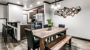 A modern kitchen with a central island, bar stools, and a dining table with chairs.