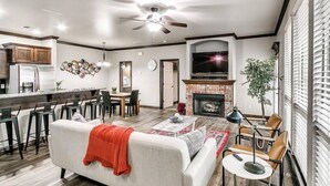A modern living room with a fireplace, a dining area, and a kitchen.