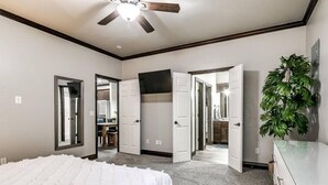 A bedroom with a bed, a ceiling fan, and a dresser.