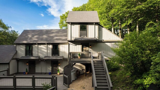 A two-story building with a wooden deck, a staircase, and a small balcony.