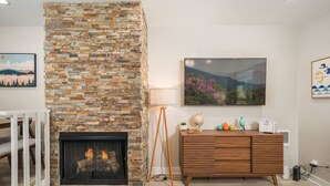 A living room with a stone fireplace, a wooden cabinet, and a painting on the wall.