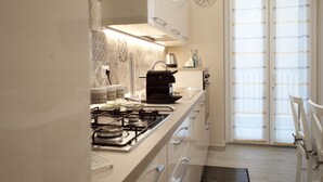 Une cuisine moderne équipée d’une cuisinière à gaz, d’une machine à café et de quelques horloges décoratives murales.