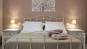 Une chambre à coucher comprenant un lit, deux tables de chevet et une œuvre d’art accrochée au mur.