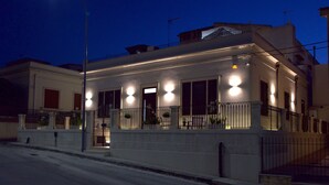 Un bâtiment à deux étages doté d’un balcon, éclairé par des lampes extérieures.