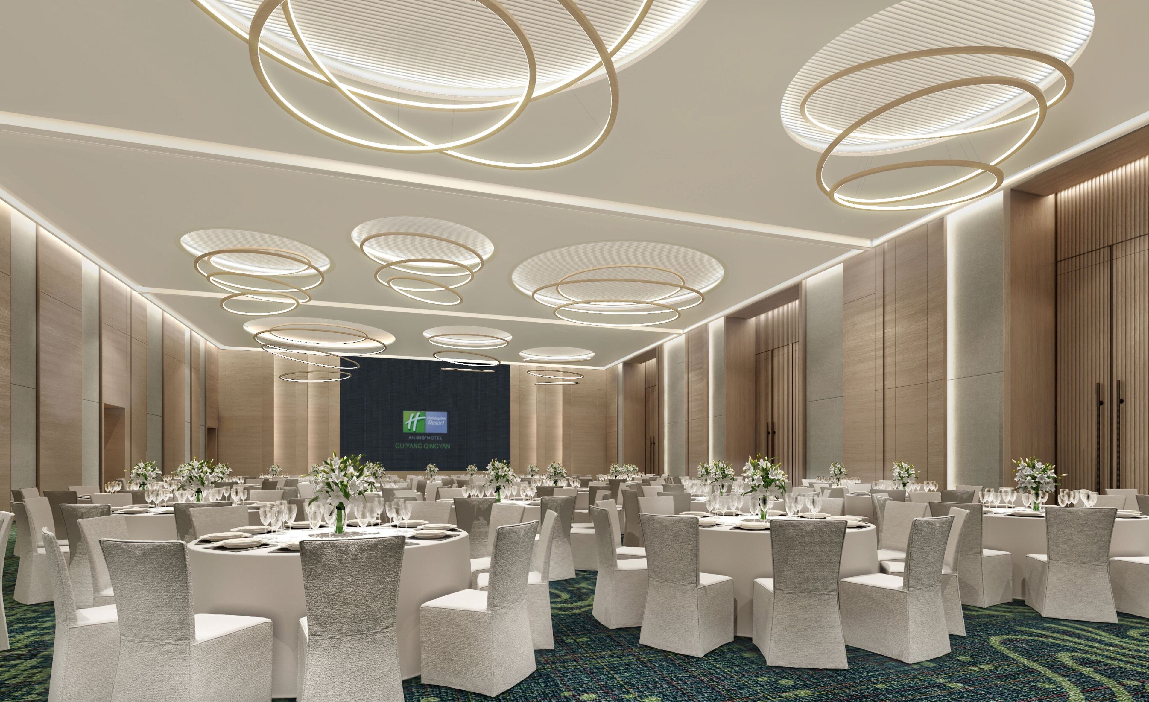 A conference room with round tables, chairs, and a large screen.