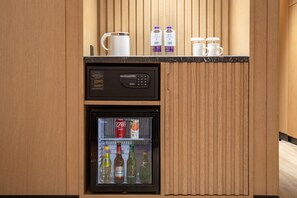 A minibar with a refrigerator containing beverages and a coffee machine.