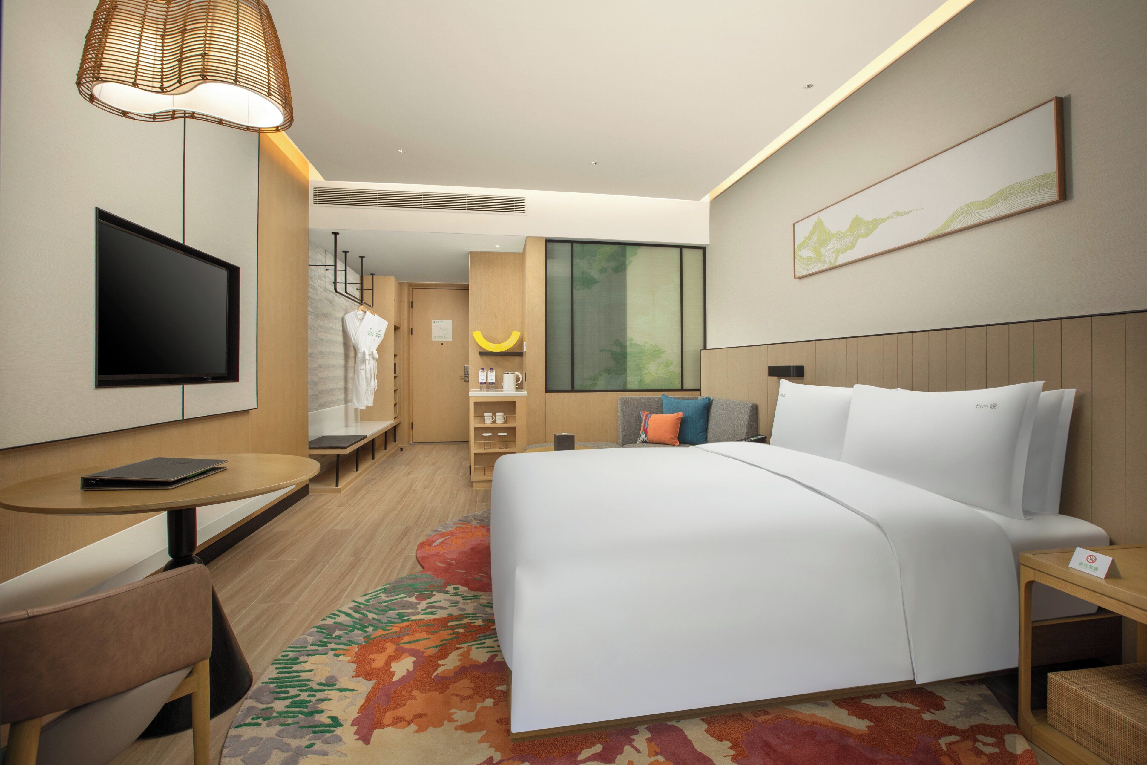 Una habitación de hotel con una cama, televisión, escritorio y una silla.