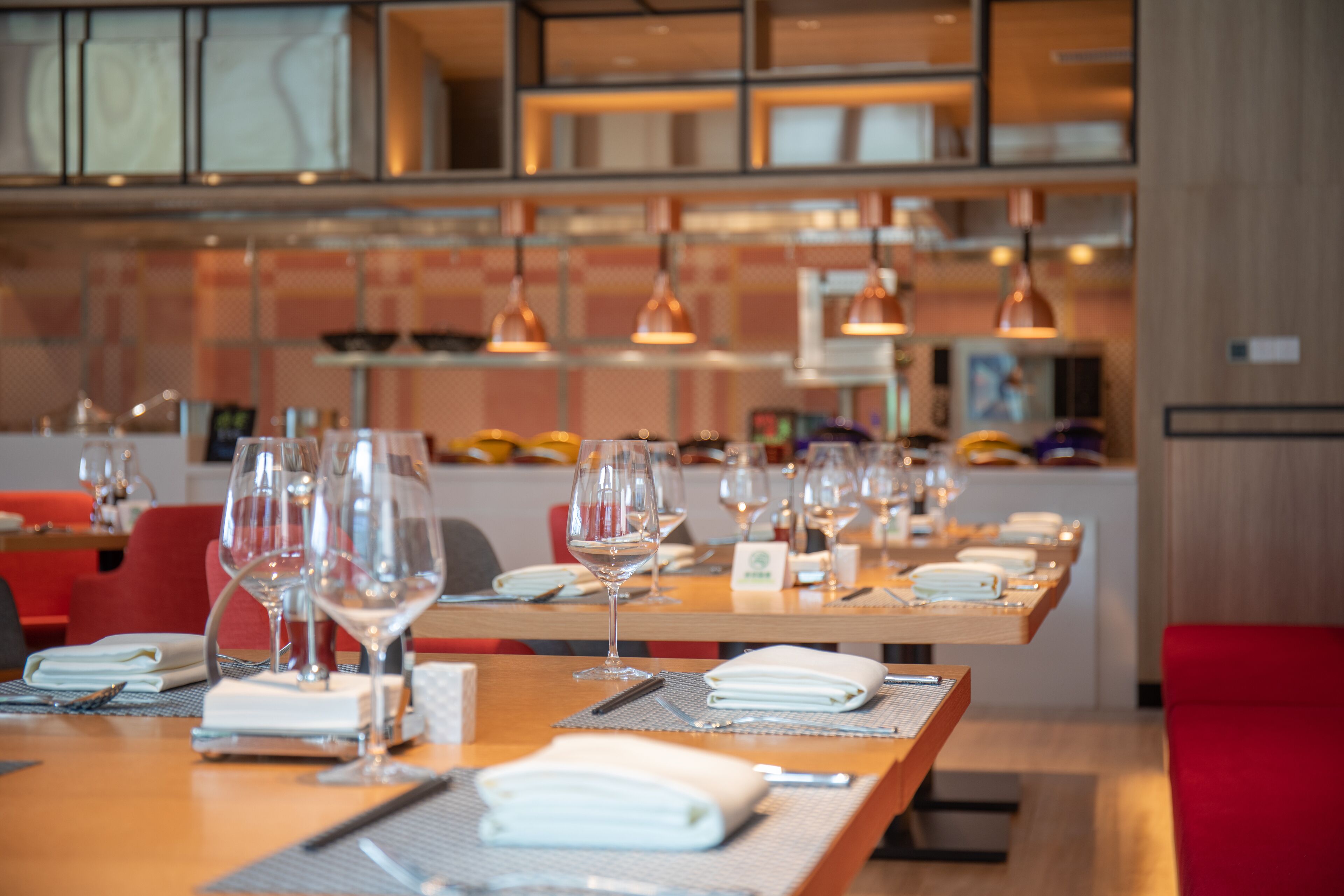 Un restaurante con varias mesas dispuestas para comer, cada una con copas de vino y cubiertos.