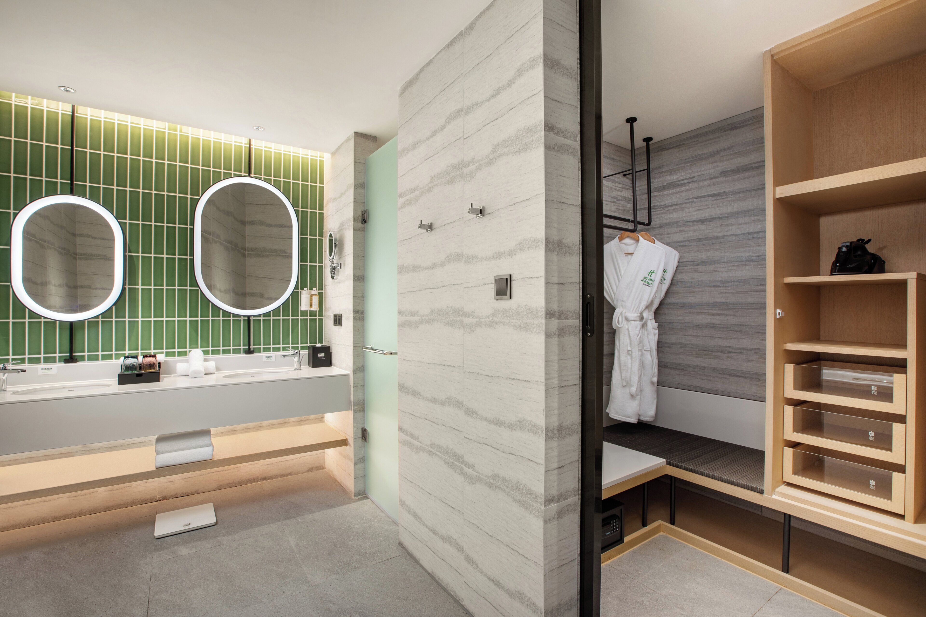 Un baño moderno con tocador, dos espejos, toallero y un mueble de almacenamiento de madera.