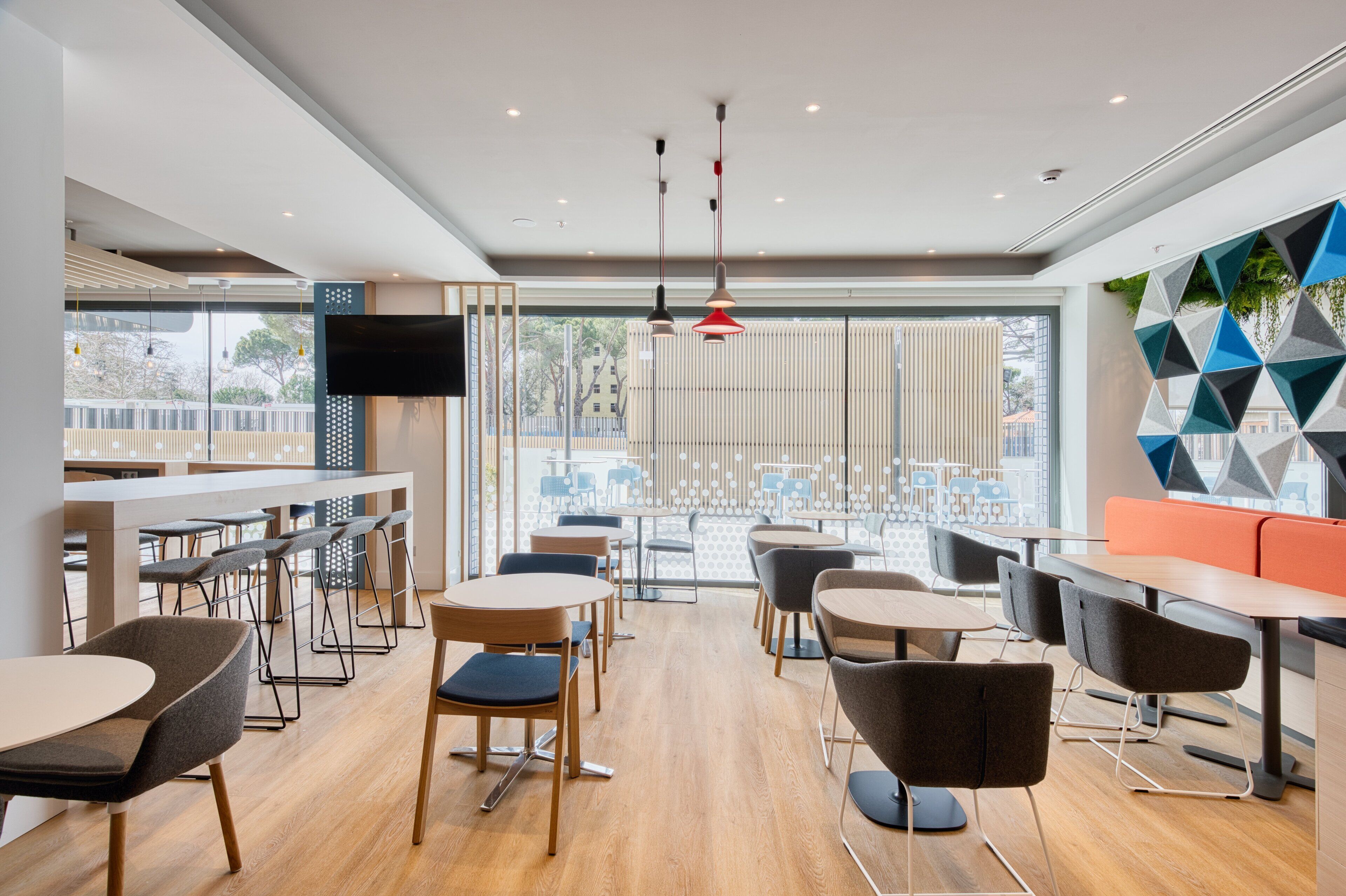 A modern dining area with wooden flooring, round tables, and contemporary chairs.