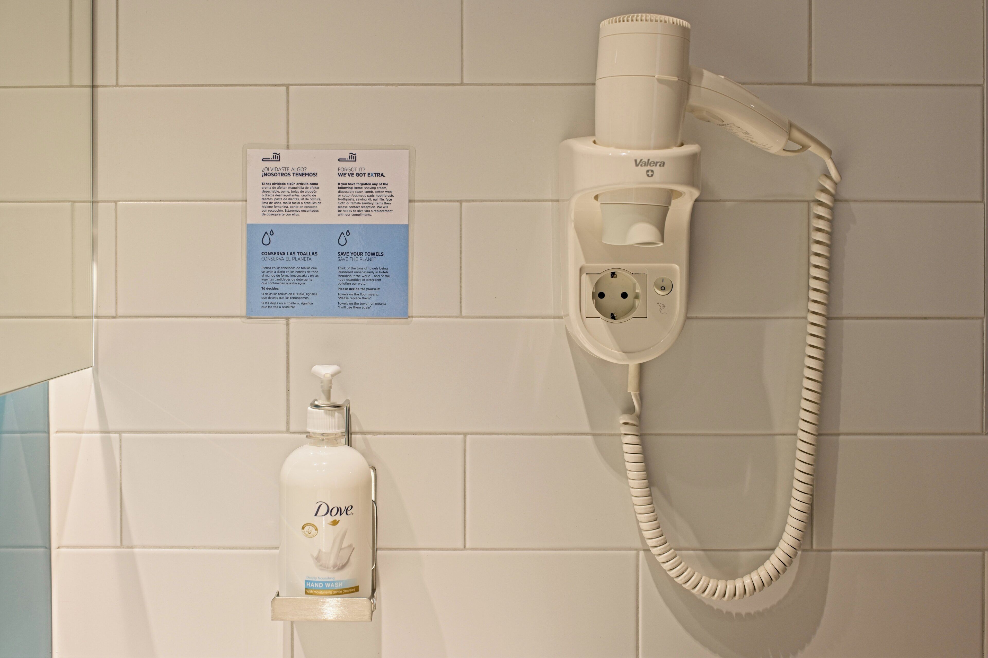Un sèche-mains et un flacon de savon pour les mains Dove sont fixés au mur.