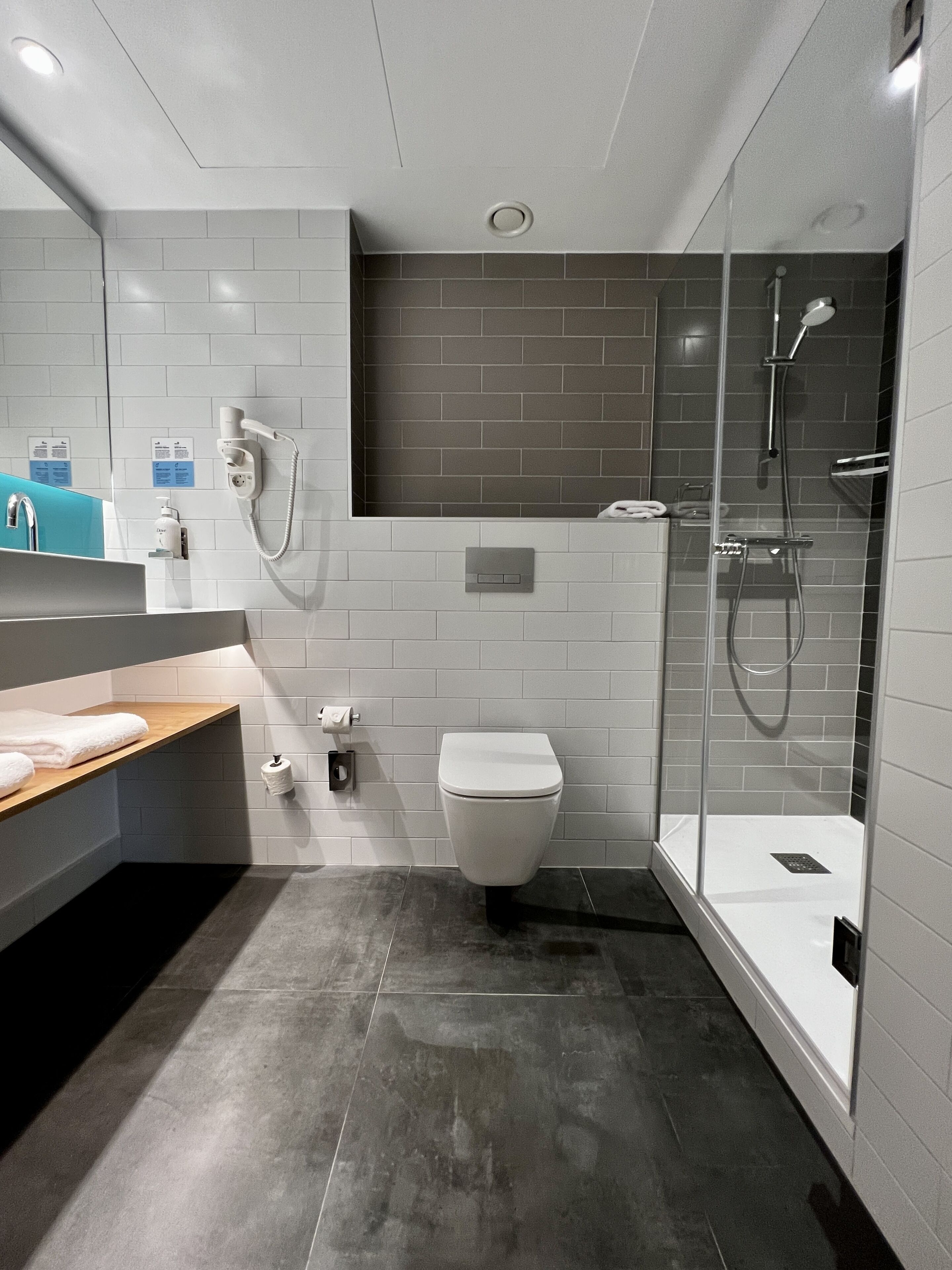 A modern bathroom with a toilet, shower, and sink.