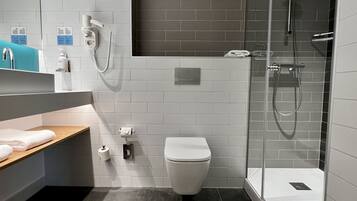A modern bathroom with a toilet, shower, and sink.