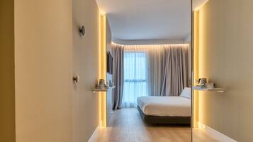 Un dormitorio moderno con una cama grande, mesitas de noche, un espejo y una ventana con cortinas.